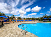 Thumbnail 42 of 51 - A swimming pool surrounded by blue lounge chairs and umbrellas.