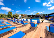 Thumbnail 43 of 51 - A sunny day at the pool with blue lounge chairs and wooden deck.