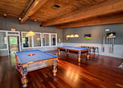 Thumbnail 50 of 51 - A pool table in a room with wooden floors and a ceiling.