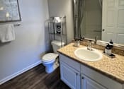Thumbnail 24 of 33 - A bathroom with a toilet, sink, mirror, and light fixture.
