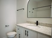 Thumbnail 28 of 33 - A bathroom with a toilet, sink, and mirror.