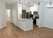 Thumbnail 26 of 33 - A kitchen with a white island and wooden floors.