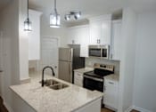 Thumbnail 27 of 33 - A kitchen with granite countertops and stainless steel appliances.