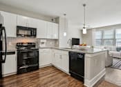 Thumbnail 3 of 69 - A modern kitchen with white cabinets and black appliances at Highline Urban Lofts Apartments, Cypress, Texas