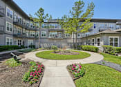 Thumbnail 36 of 69 - A courtyard with a circular walkway and a small garden in the middle of apartment buildings. at Highline Urban Lofts Apartments, Cypress, TX, 77429
