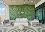 Thumbnail 22 of 39 - A white sofa and two chairs are arranged on a striped rug in front of a green wall with the word "CARTER" on it.
