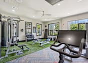 Thumbnail 51 of 69 - A gym with a variety of equipment including treadmills, weights, and a television at Highline Urban Lofts Apartments, Cypress