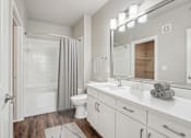 Thumbnail 6 of 69 - A white bathroom with a toilet, sink, and shower at Highline Urban Lofts Apartments, Cypress, TX, 77429