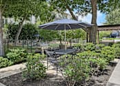 Thumbnail 25 of 48 - A patio with a table and chairs under an umbrella at Everra Midtown Park Apartments, Dallas, TX, 75231