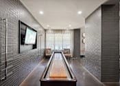 Thumbnail 31 of 69 - A long hallway with a shiny wooden table in the middle and a television on the wall at Highline Urban Lofts Apartments, Texas, 77429