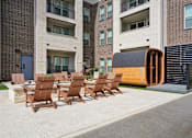 Thumbnail 29 of 39 - A modern outdoor seating area with chairs and a table is set up in front of a building.