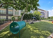 Thumbnail 20 of 48 - A playground with a green slide and a tent in the background at Everra Midtown Park Apartments, Dallas, TX, 75231