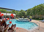 Thumbnail 57 of 69 - A pool surrounded by trees and a building in the background at Highline Urban Lofts Apartments, Cypress, TX