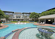 Thumbnail 35 of 69 - A large swimming pool with a fountain in the middle of it at Highline Urban Lofts Apartments, Cypress 77429