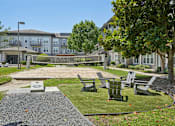 Thumbnail 41 of 69 - A playground area with a slide and seating area in front of a building at Highline Urban Lofts Apartments, Texas