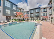 Thumbnail 40 of 53 - Outdoor swimming pool courtyard with lounge chairs at The Barton Apartments, Texas