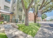 Thumbnail 47 of 53 - Building exterior with shaded courtyard lawn at The Barton Apartments, Dallas, TX