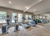 Thumbnail 52 of 69 - A gym with treadmills, elliptical machines, and stationary bikes.