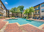 Thumbnail 48 of 69 - A swimming pool surrounded by brick walkways and residential buildings.