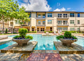 Thumbnail 39 of 69 - A large apartment complex with a pool in the foreground.
