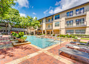 Thumbnail 49 of 69 - A pool surrounded by a brick patio and a building in the background.