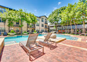 Thumbnail 38 of 69 - Two lounge chairs sit on a brick patio next to a pool.
