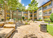Thumbnail 50 of 69 - A stone walkway leads through a landscaped courtyard with a trash can and trees.