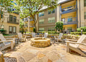 Thumbnail 46 of 69 - A courtyard with a fire pit surrounded by chairs and trees.