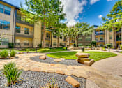 Thumbnail 61 of 69 - A sunny day at a residential complex with a well-maintained garden and a stone pathway.