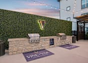 Thumbnail 27 of 53 - wall of greenery with a Vineyard sign at Vine + Vail Townhomes and Apartments, Grapevine