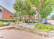 Thumbnail 36 of 42 - A brick wall with a flower bed in front of a building at Copper Hill Apartments, Bedford 76021
