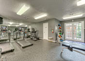 Thumbnail 17 of 42 - A gym with treadmills, exercise equipment, and a mirrored wall at Copper Hill Apartments, Texas, 76021