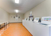 Thumbnail 23 of 42 - A laundromat with a row of washers and dryers at Copper Hill Apartments, Texas