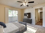 Thumbnail 11 of 42 - A bedroom with a bed, a ceiling fan, and a television at Copper Hill Apartments, Bedford