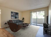 Thumbnail 9 of 42 - A living room with a brown chair and a grey couch at Copper Hill Apartments, Texas, 76021