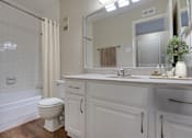 Thumbnail 7 of 42 - A white bathroom with a toilet, sink, and shower at Copper Hill Apartments, Texas