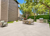 Thumbnail 32 of 53 - Outdoor grilling area with dining tables and lawn games at The Barton Apartments, Dallas
