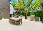 Thumbnail 29 of 53 - Outdoor kitchen with grills and dining table at The Barton Apartments, Dallas, TX