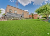 Thumbnail 32 of 37 - Spacious lawn area with community building at Vue Live Oak Apartments, Texas
