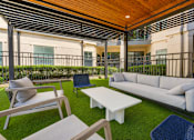 Thumbnail 45 of 69 - A patio with a white couch, chairs, and tables.
