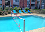 Thumbnail 18 of 39 - A pool with a red net in front of a brick building.