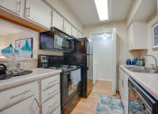 Thumbnail 5 of 57 - a kitchen with black appliances and white cabinets at Indian Creek Apartments, Texas