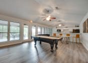 Thumbnail 21 of 57 - an open living room with a pool table and a kitchen with windows at Indian Creek Apartments, Carrollton, TX, 75007
