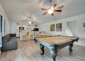 Thumbnail 22 of 57 - a living room with a pool table and a kitchen with a bar at Indian Creek Apartments, Texas