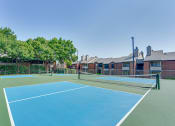 Thumbnail 40 of 57 - two tennis courts with apartments in the background at Indian Creek Apartments, Carrollton, Texas