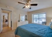 Thumbnail 8 of 57 - a bedroom with a bed and a ceiling fan at Indian Creek Apartments, Carrollton, Texas