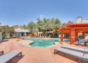 Thumbnail 37 of 57 - a swimming pool with a wooden deck with tables at Indian Creek Apartments, Carrollton, TX, 75007