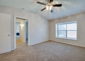Thumbnail 54 of 57 - an empty living room with a ceiling fan and a window at Indian Creek Apartments, Carrollton, TX