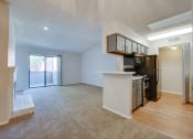Thumbnail 47 of 57 - an empty living room with a kitchen and a door to a balcony at Indian Creek Apartments, Carrollton, TX, 75007