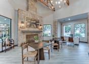 Thumbnail 45 of 68 - A modern dining room with a stone fireplace and wooden furniture at Limestone Ranch Apartments, Texas